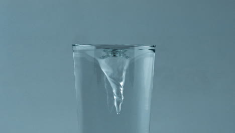 clear cold water vortex inside glass container closeup. ice cocktail spinning