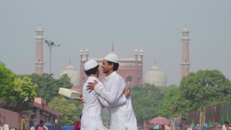 muslim men celebrating eid and exchanging gifts in front of mosque