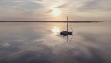 Side-panning-shot-of-sailing-yacht-cruising-on-Lauwersmeer-in-the-early-morning,-aerial