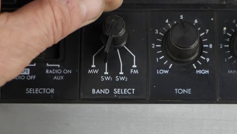 male hand rotates the band selection control knob. old, retro receiver.