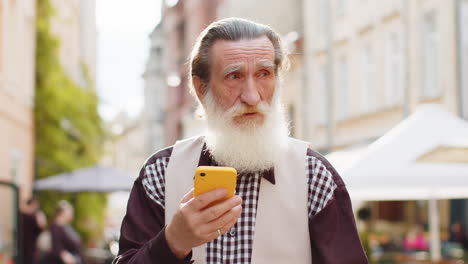 hombre de edad avanzada usa teléfono inteligente escribe mensajes de texto navega por internet termina el trabajo conversa en línea