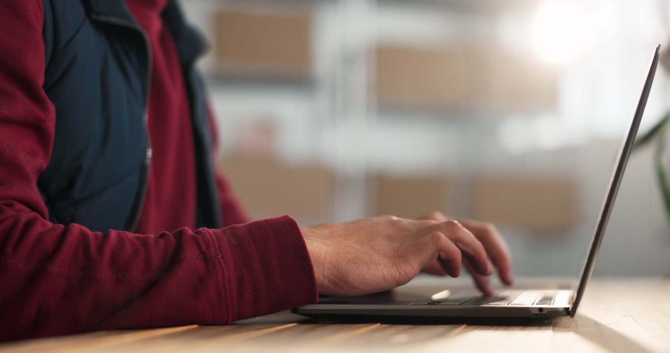 Person Typing on Laptop in Warehouse Office