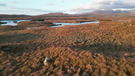 aerial dolly shot of the scenic landscape of ireland at the connemara lakes with a view of the wide landscape in autumnal golden tones and the reflecting lake at the golden hour