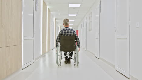 man in wheelchair in hospital corridor