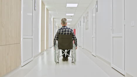 hombre en silla de ruedas en el pasillo del hospital