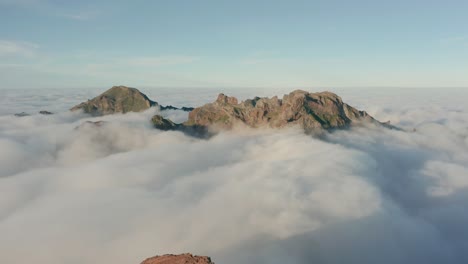 sea of clouds surrounding tall mountain peaks of madeira island, aerial