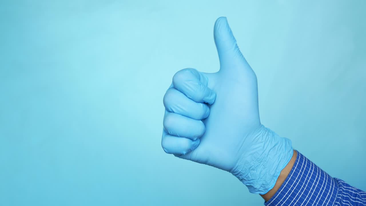 mano con guantes azules dando un pulgar hacia arriba
