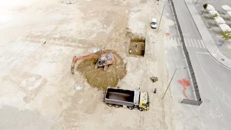 backhoe and truck at the construction site with laborers working - aerial drone