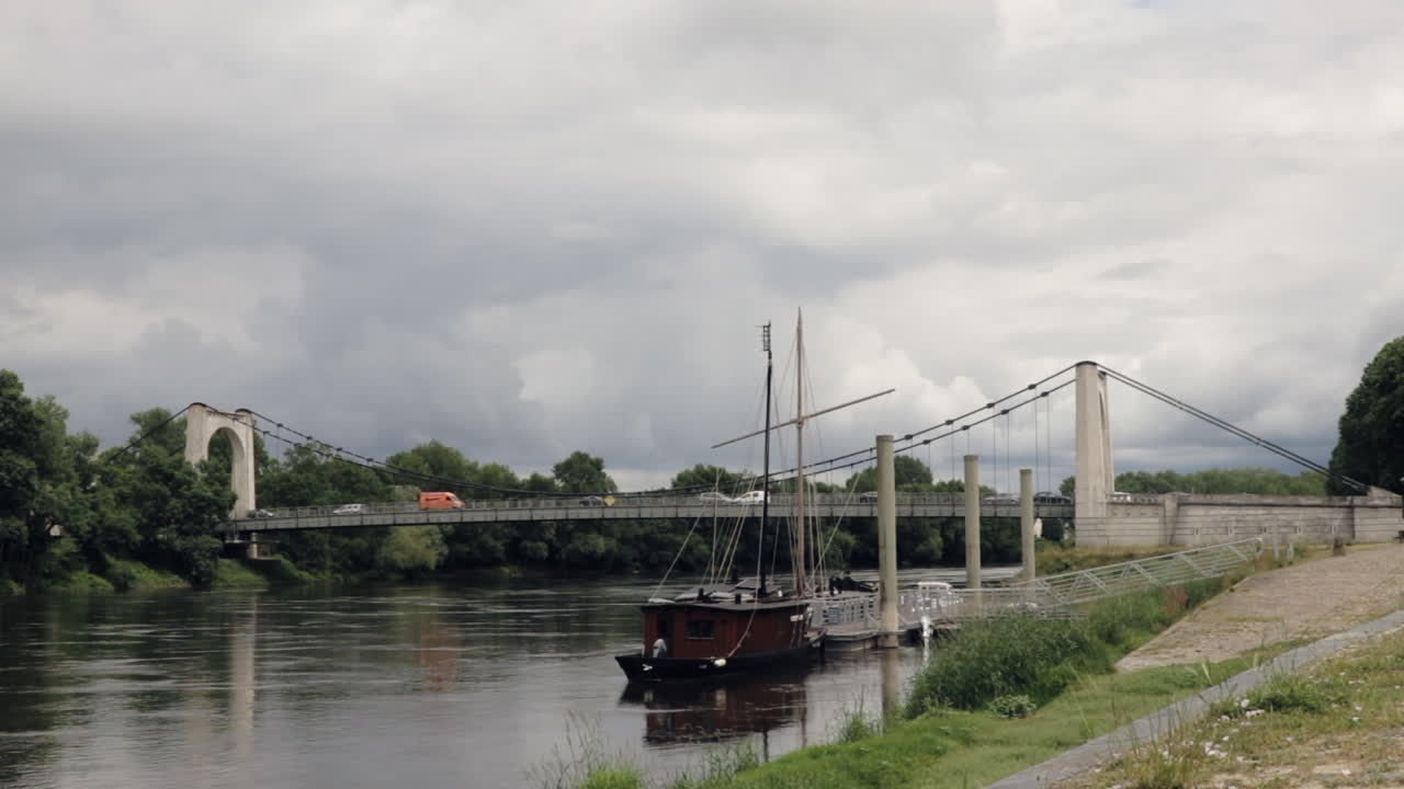 프랑스 마을에 묶여 있는 아름다운 보트로 이동하는 모습과 배경의 돌다리 위로 자동차가 지나가는 모습