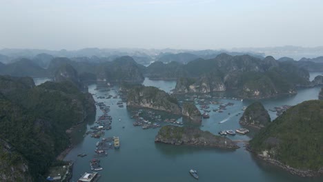 Small-boat-motors-past-Van-Gia-fishing-village-in-La-Han-Bay,-Vietnam