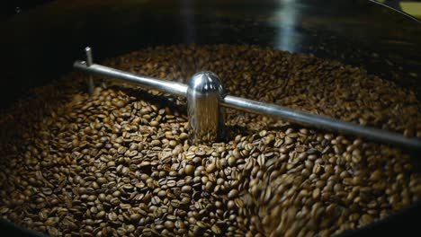 los granos de café se revuelven en la placa de enfriamiento después de tostarlos a media altura