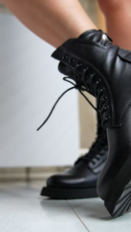 leather army fashionable stylish black boots demonstrated by the female model. woman turning her feet in front of camera. close up. vertical video