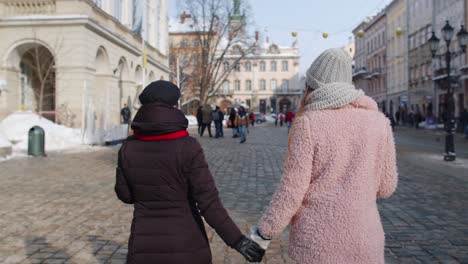 two women friends enjoying a coffee together in a snowy city square