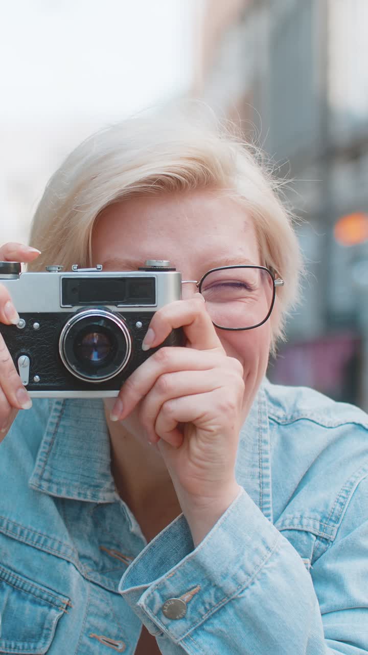 Ritratto di una giovane donna turistica felice che scatta foto usando una fotocamera retro in una strada urbana della città