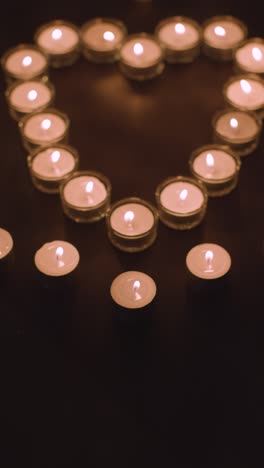 Vertical-Video-Of-Romantic-White-Candles-In-the-Shape-Of-A-Heart-On-Black-Background