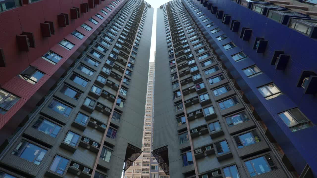 Vista panorâmica de edifícios de apartamentos e arranha-céus no centro de Hong Kong, China, em um dia ensolarado, mostrando a densidade da vida urbana e a arquitetura moderna.