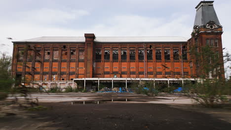 Decayed-industrial-building-in-Europe,-aerial-fly-backward-view