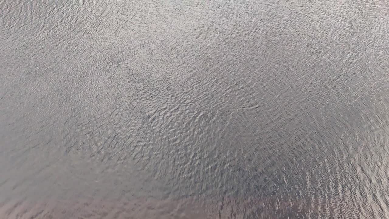 Aerial drone glides over Scottish wetland toward tranquil lake under soft daylight in summer