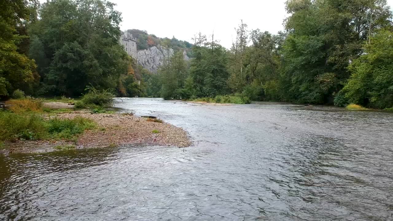 Drone che sorvola un fiume con lo Chateau De Walzin, un castello da fiaba