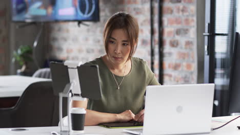 Asiatischer-Senior-Berufstätiger-Schaut-Auf-Laptop,-Trägt-Grünes-Oberteil