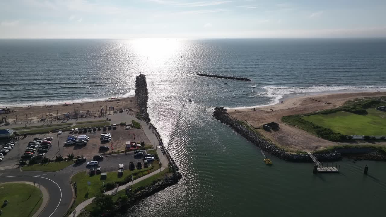 pequeños barcos saliendo de la entrada de rudee hacia el océano atlántico hacia el sol