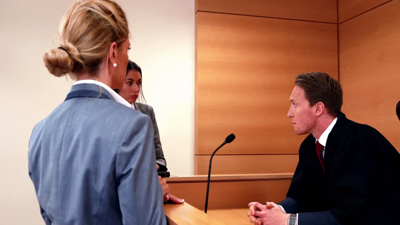 심각한 판사가 두 명의 변호사와 이야기하고 있습니다.