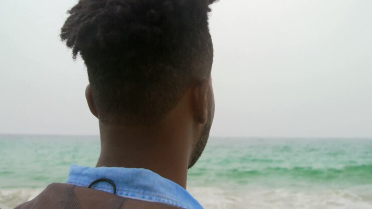 Vista posteriore di uomo afroamericano in piedi sulla spiaggia 4k