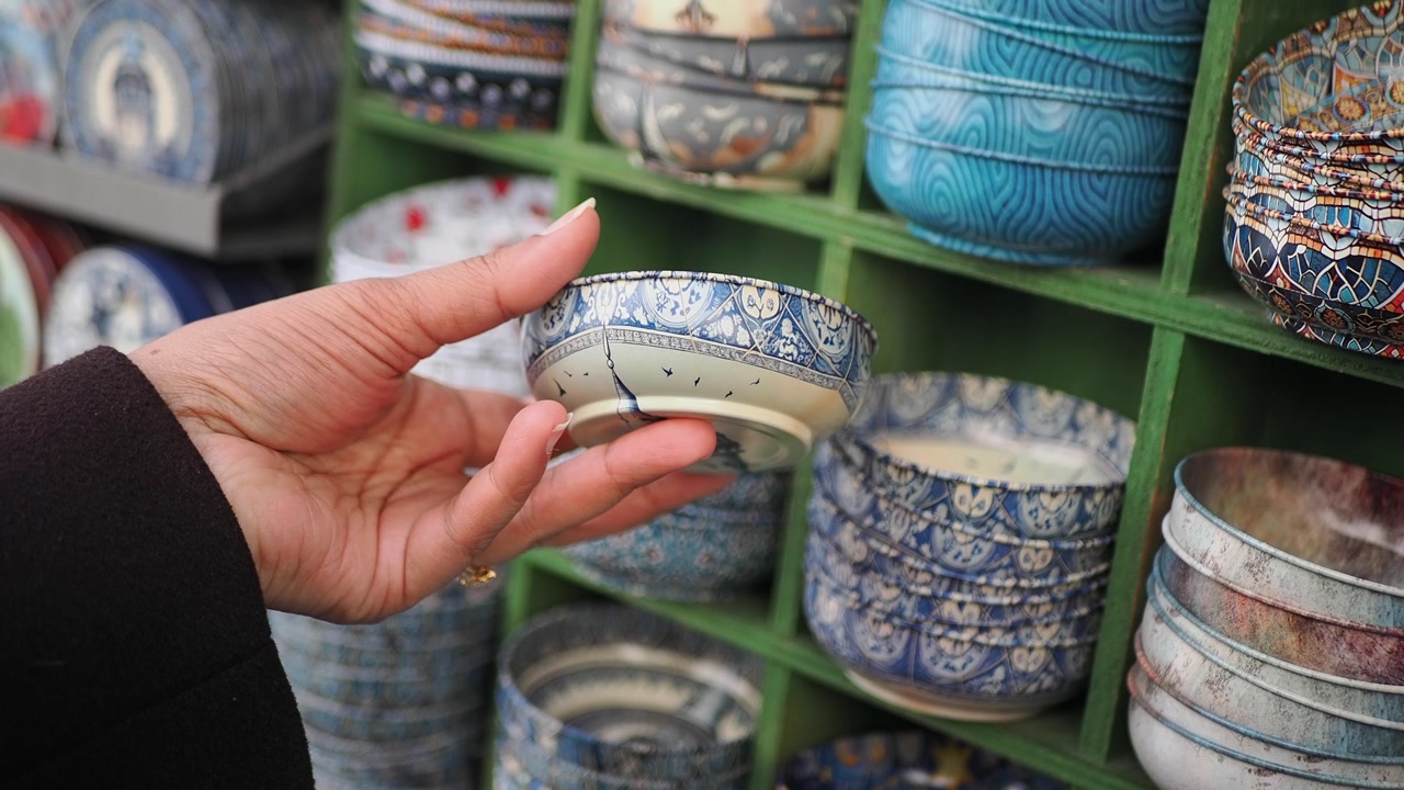 Hand Examining Small Decorative Bowls on a Shop Shelf
