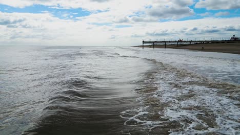 Englischer-Touristischer-Badeort,-Aufgenommen-Mit-Einer-Drohne,-Die-Einen-Hohen-Luftbildpunkt-Bietet,-Der-Einen-Weiten-Sandstrand-Mit-Einem-Pier-Und-Tosenden-Wellen-Zeigt