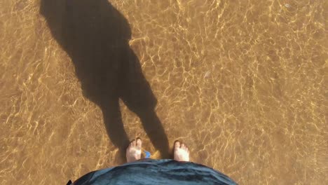 standing with the feets in the sea as the waves crashing into the legs. filmed from up down.