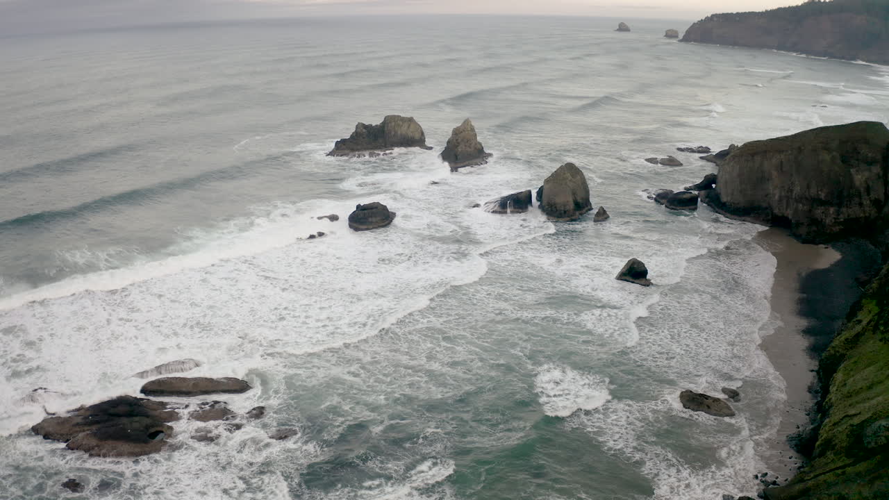 Vista panoramica di una costa frastagliata con onde che si infrangono e faraglioni distintivi