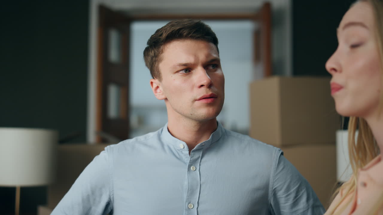 젊은 커플이 집에서 싸우고 있습니다. 긴장한 남자에게 주장을 하는 여자.