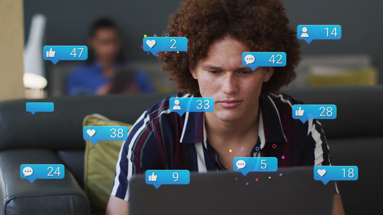 animación de iconos de las redes sociales flotando sobre un hombre biracial pensativo usando una computadora portátil en la oficina.