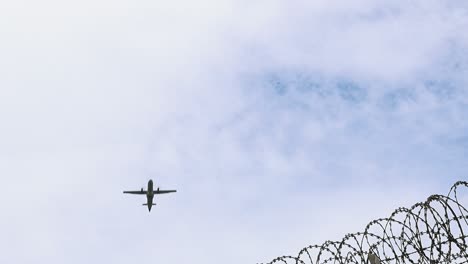 avión despegando sobre el alambre de púas en un fondo nublado