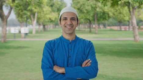 happy muslim man standing crossed hands in park