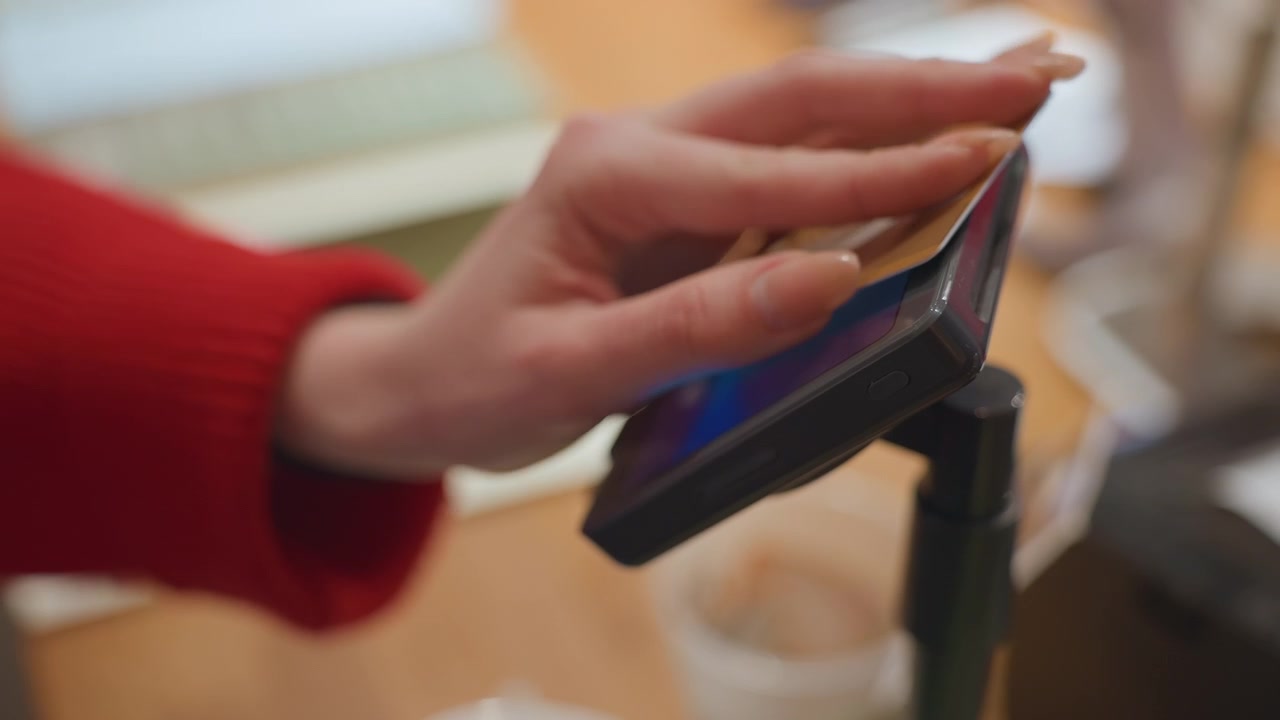 Woman's Hand Swiping Credit Card on a Mobile Payment Terminal