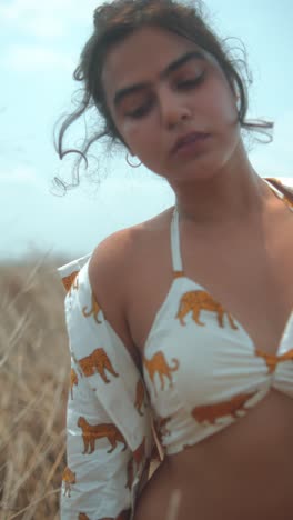 young woman in a field, wearing a shirt with tiger print, looking serene and relaxed
