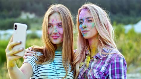 retrato de las alegres y bonitas chicas rubias sonriendo a la cámara del smartphone mientras toman fotos selfie