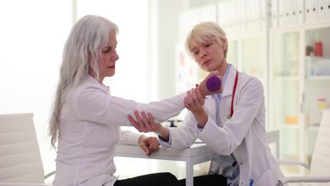 physical therapy session: doctor assists patient with arm exercise