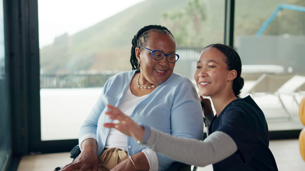 Happy Elderly Woman in Wheelchair with Caregiver Looking Out Window