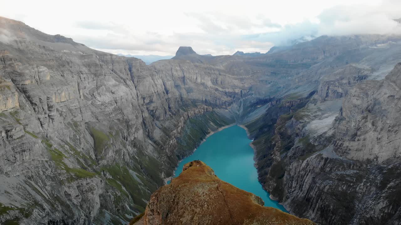 un paso elevado sobre un mirador sobre el lago limernsee en glarus, suiza, con excursionistas disfrutando de la vista de los alpes suizos con acantilados y picos después del atardecer desde su campamento