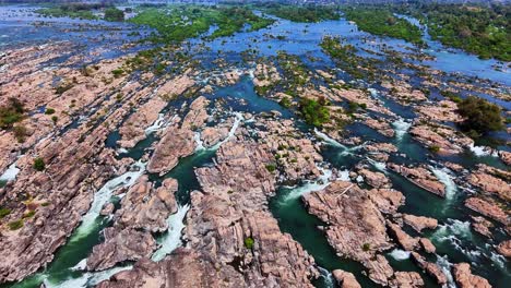 wide top-down drone shot over mekong river near don det, laos, reveals interwoven rapids cutting through jagged rock beds and narrow channels across the fractured floodplain of the si phan don region
