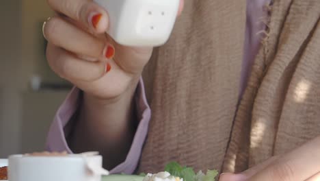 mujer añadiendo sal a la comida