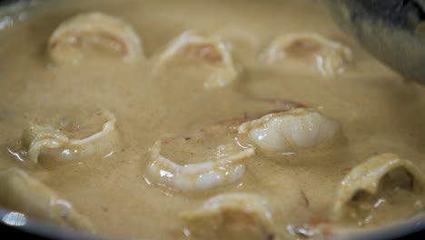 fresh prawns turn red while cooking in coconut cream curry - close up