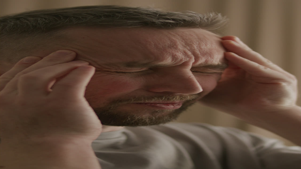 Primo piano di uomo che si massaggia le tempie a causa di mal di testa e stress