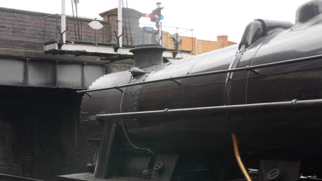 a steam engine train at a station with smoke leaving the chimney