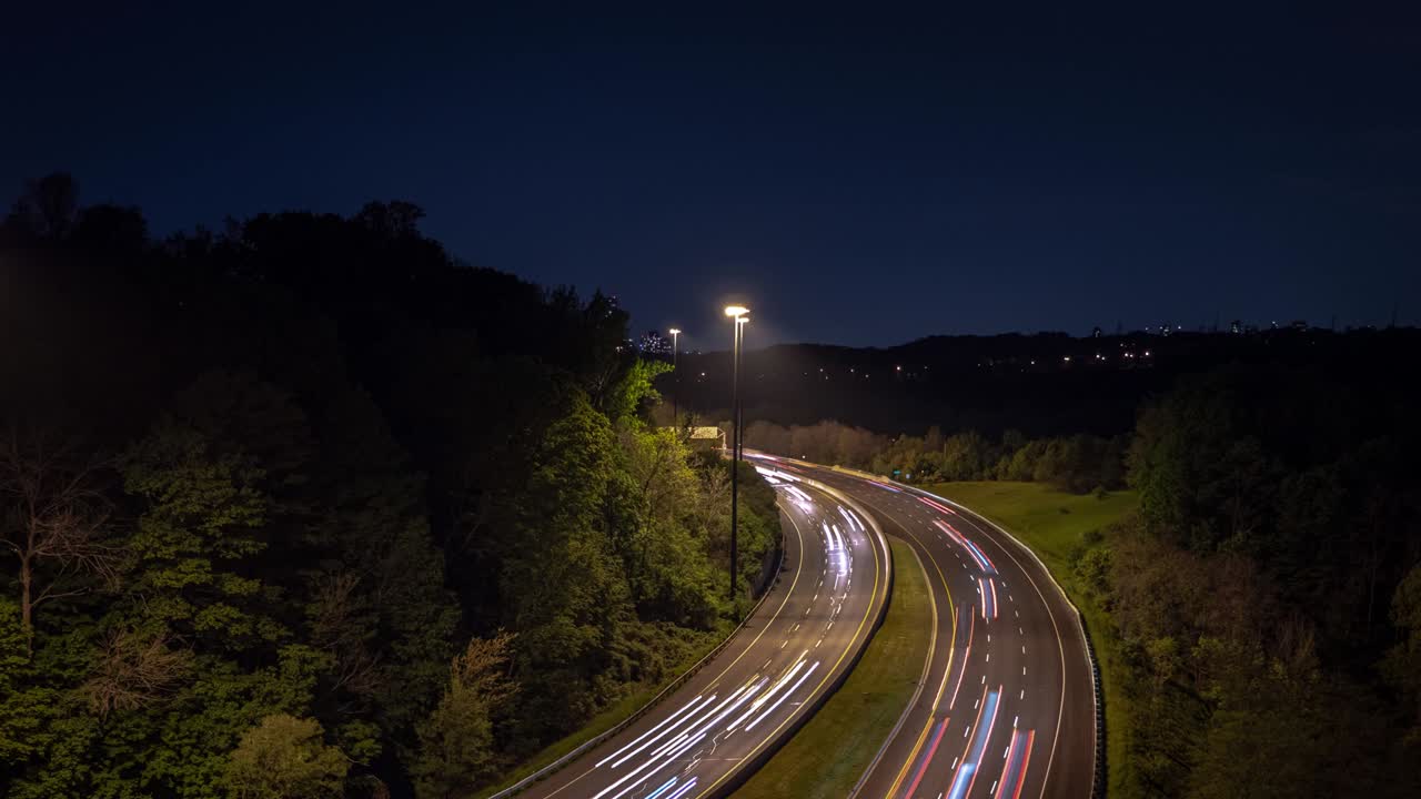 토론토 시내로 향하는 구부러진 고속도로 도로에서 빛의 흔적, 헤드라이트 및 뒷등의 긴 노출 시간 간격으로 밤에 도로 을 고 있는 나무와 함께