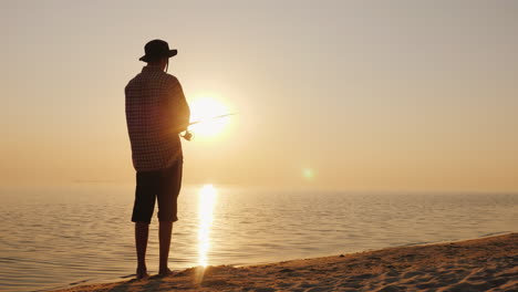 a young man is fishing on the shore of a picturesque lake at sunset 4k video