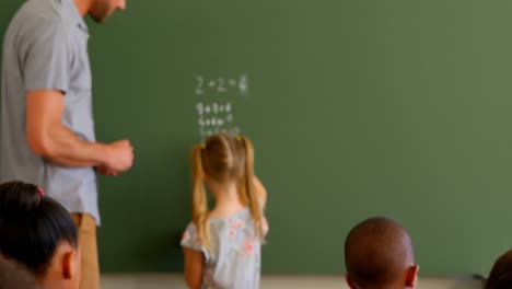joven maestro de escuela caucásico y colegiala resolviendo problemas de matemáticas en la pizarra 4k