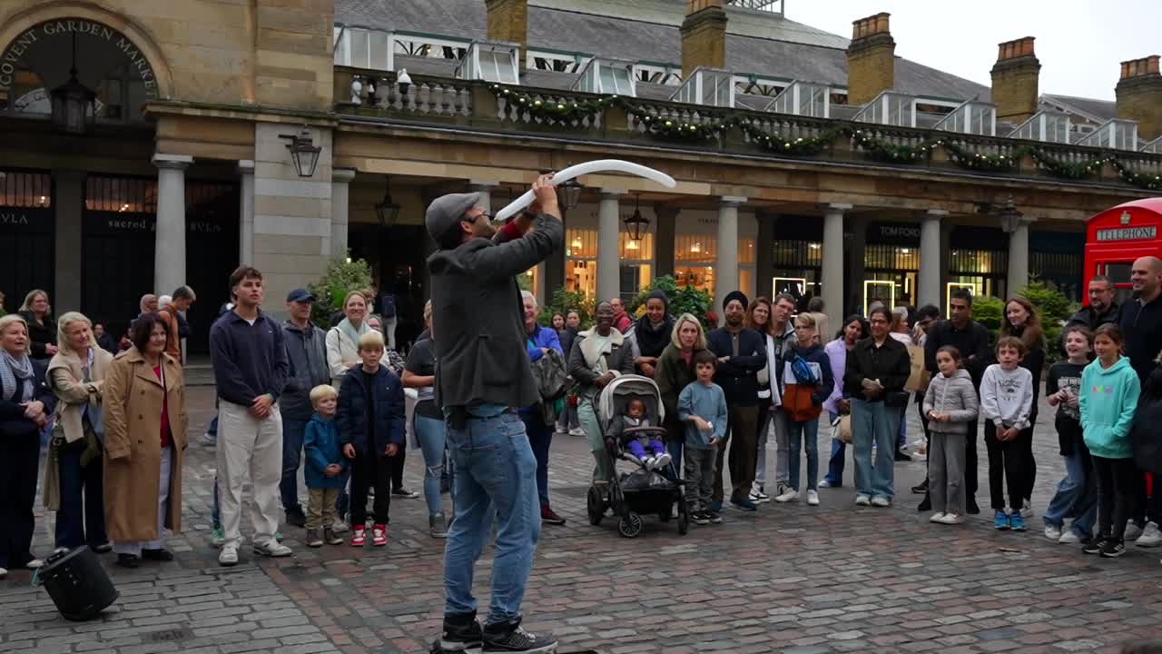 Street performer entertains a crowd with balloon tricks at Covent Garden in London